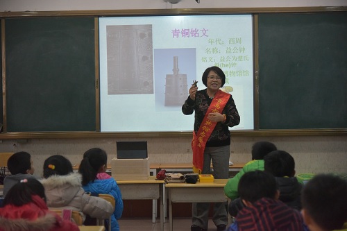 19.2016年12月，“千古探秘校园行”活动走进李沧路小学，张新平老师配合宣讲内容为同学们展示青铜器工艺品.JPG